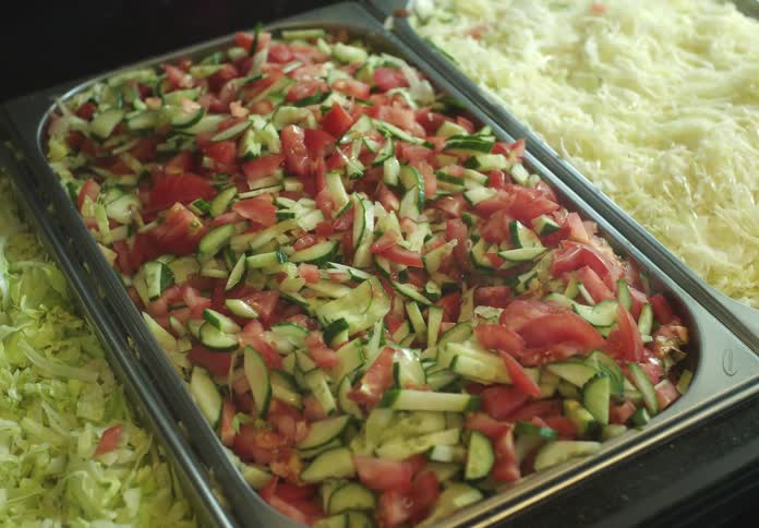 Hand with a spatula picking up salad in a restaurant
