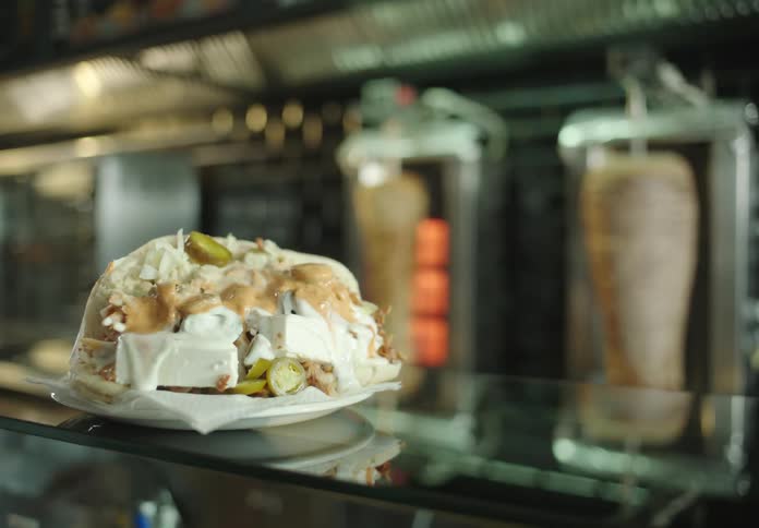 Plate full of food being placed on top of a glass counter in a restaurant