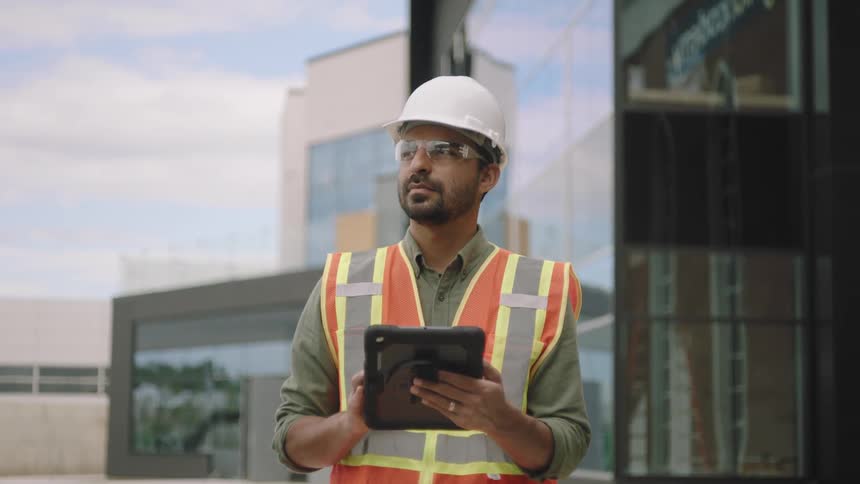 Man holding a tablet and wearing a protective helmet