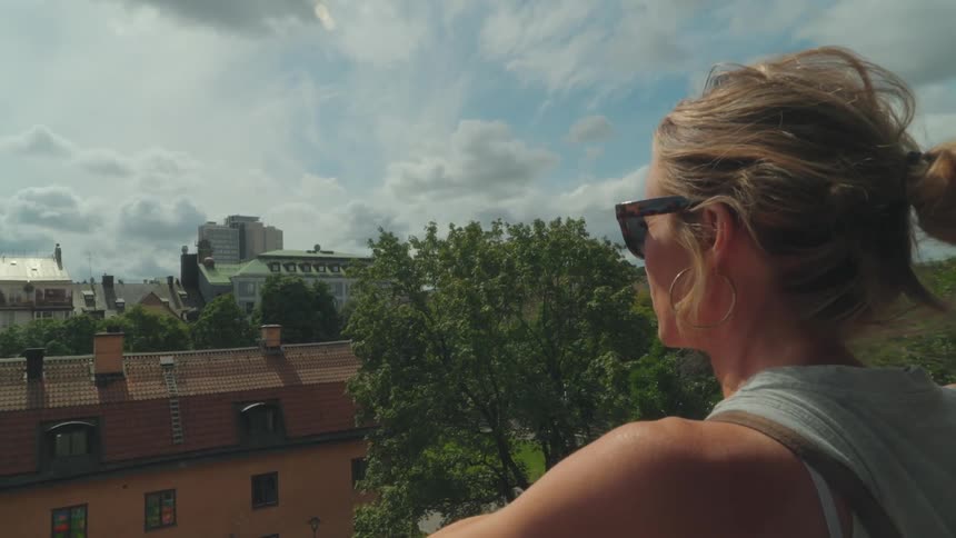 Woman wearing sunglasses and looking at a panorama of an urban city