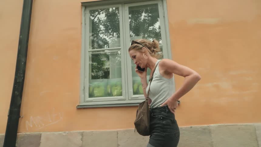 Woman walking on city street finishing a call and putting smartphone in bag