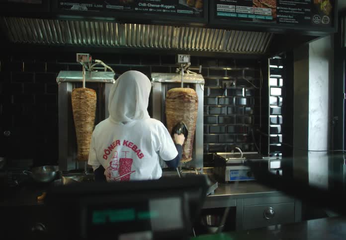 Woman cutting fillets of meat that is being roasted on a counter in a restaurant