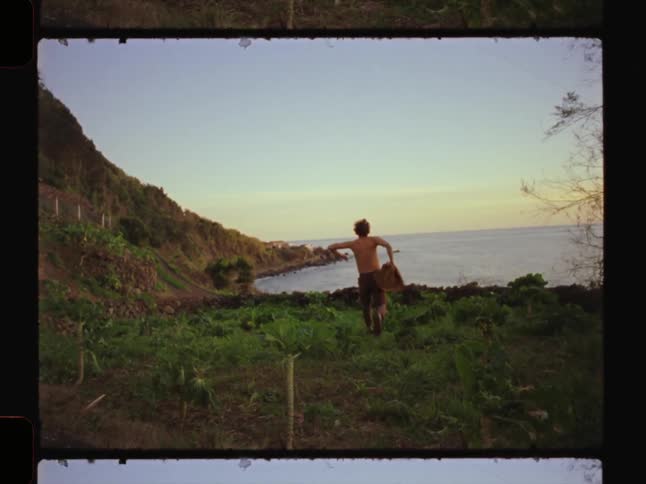 Man running taking off his shirt and heading towards the sea