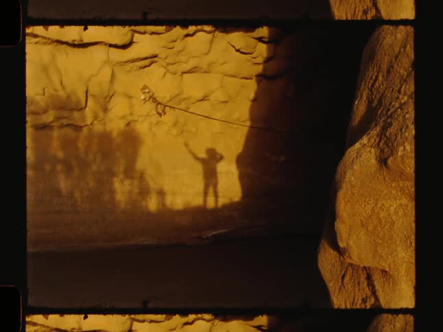Shadow of a person moving their arms on a rock