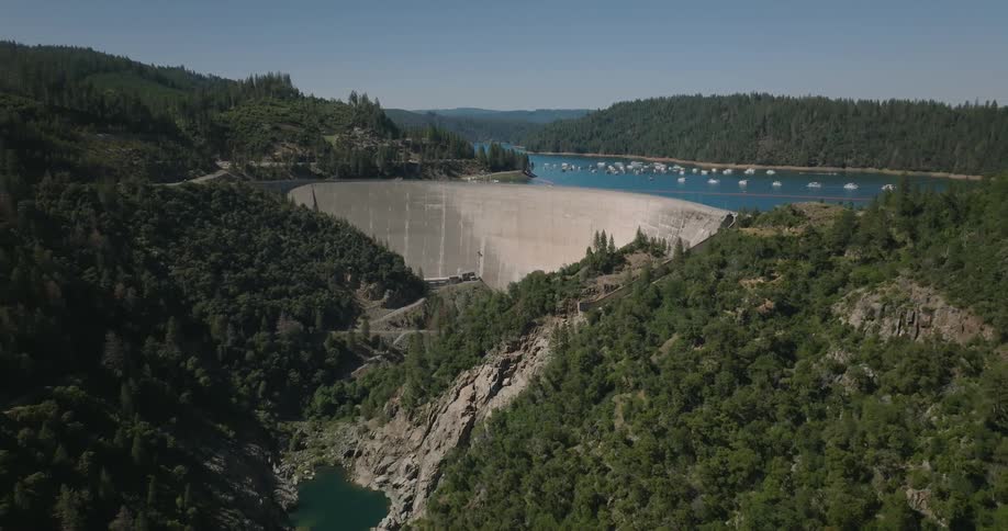 Aerial view of a barrier dividing the sea with mountains and forests around it