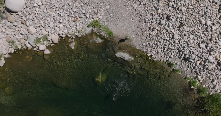 Overhead view of a person entering a lake surrounded by rocks
