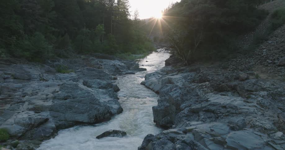A river flowing through a rocky gorge with the sun setting in the background