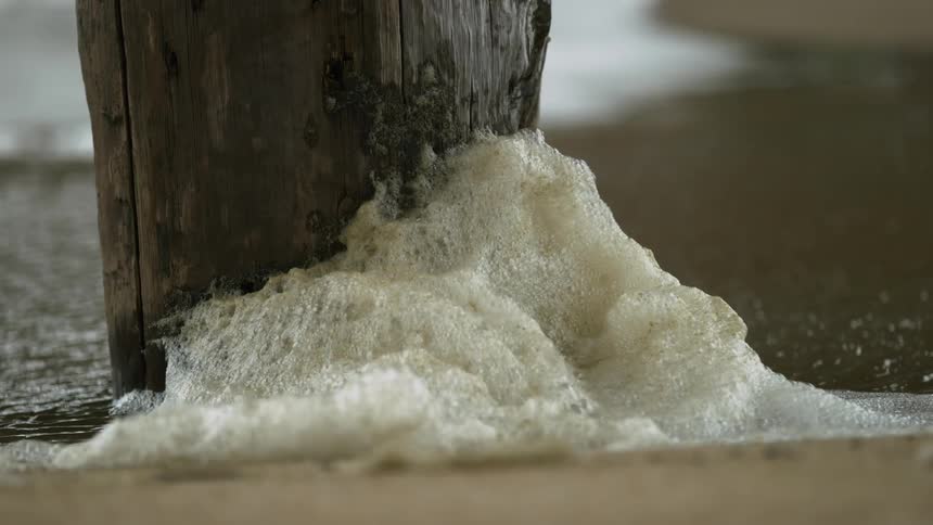 Foam building up in the water next to a pier leg