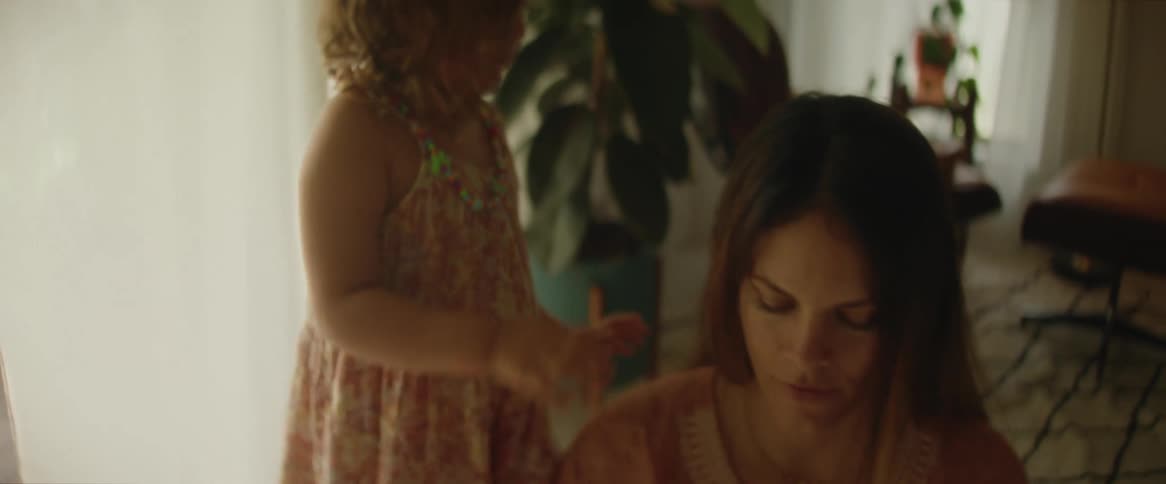 A young girl playing with her mothers hair