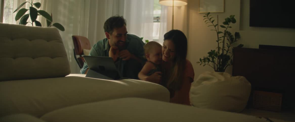 Happy couple and their baby play with a tablet in the living room