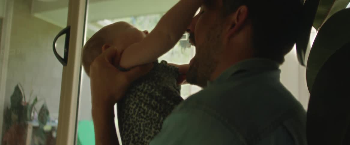 A mother letting go of her baby daughter who walks toward her father and receives hugs