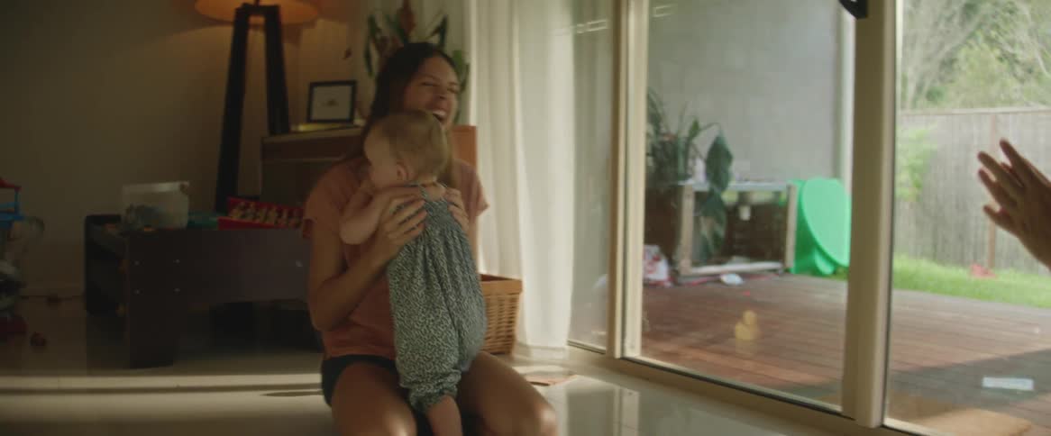 Father claps as his toddler walks across floor toward her mother