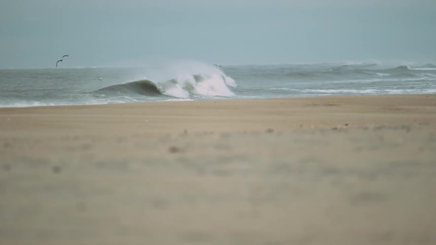 A wave crashes towards the beach