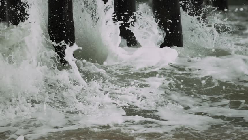 Water crashes against dock poles