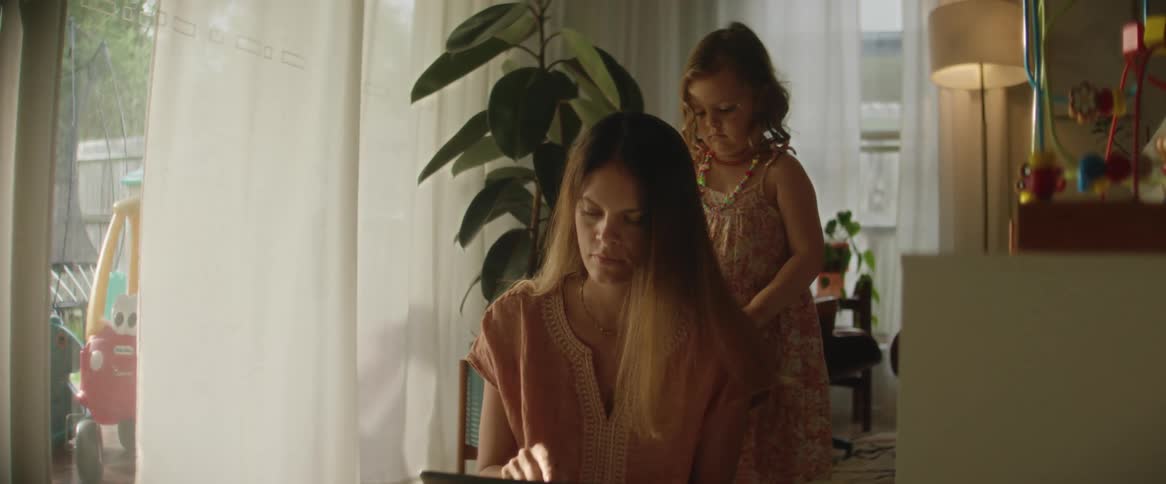 A mother sitting while her daughter plays with her hair