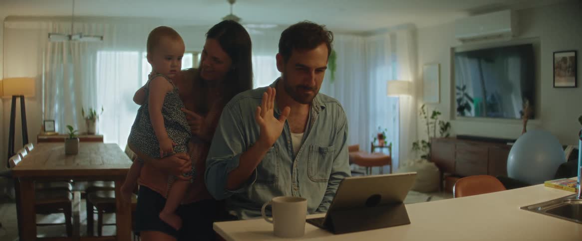 A family on a video call waving at the caller