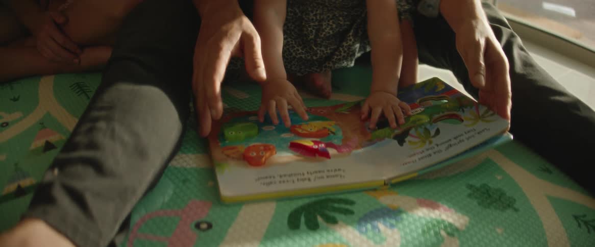 A father and a baby siting on a mat and reading a book