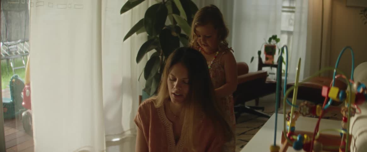A mother is sitting while the daughter plays with her hair