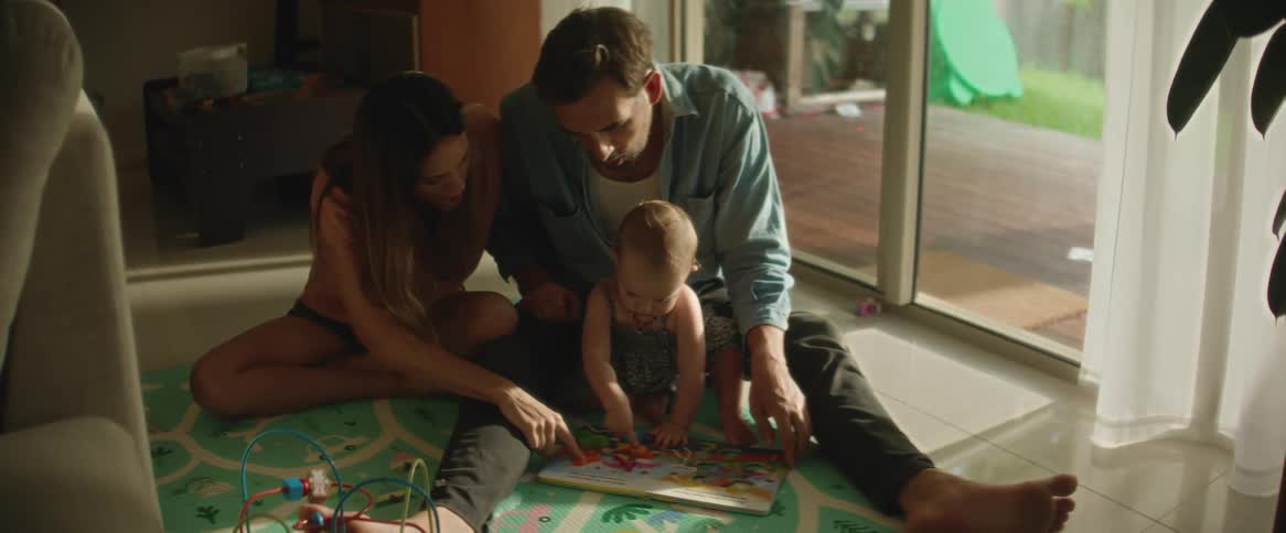 Parents sitting on the floor playing with their baby daughter