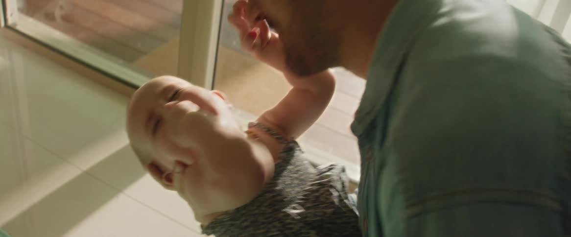 A father playing with his baby daughter indoors