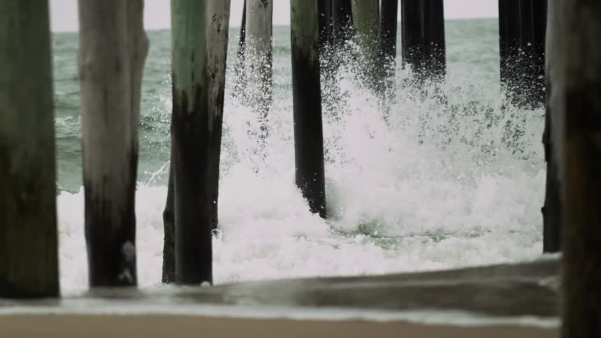 Waves crash into beach pillars