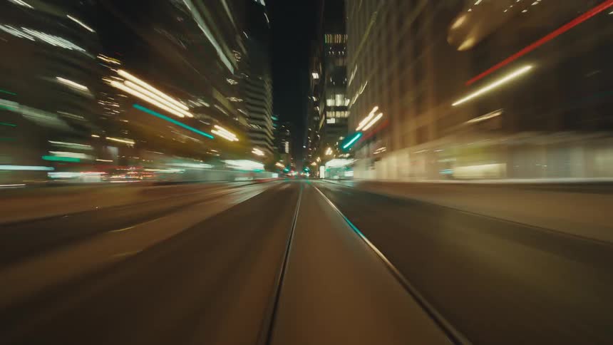 Moving view of streets of a metropolis with large buildings lit up at night
