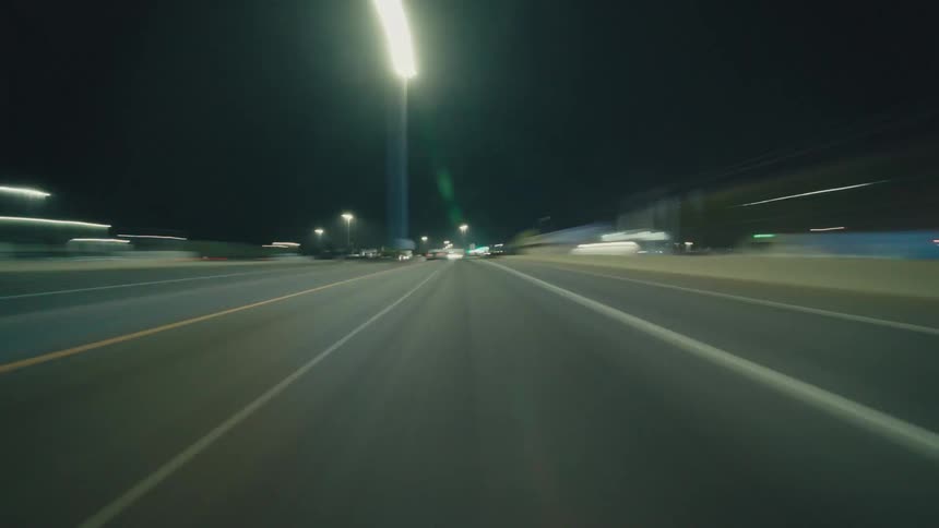 Traffic moves along a highway passing through the city at night