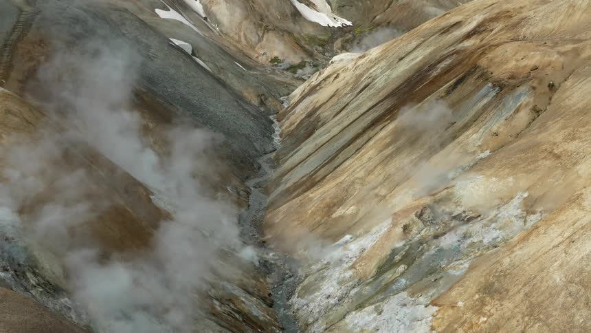 White smoke coming out of a valley between two rocky mountains