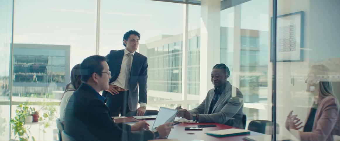 Workers in an office listen to a woman speaking