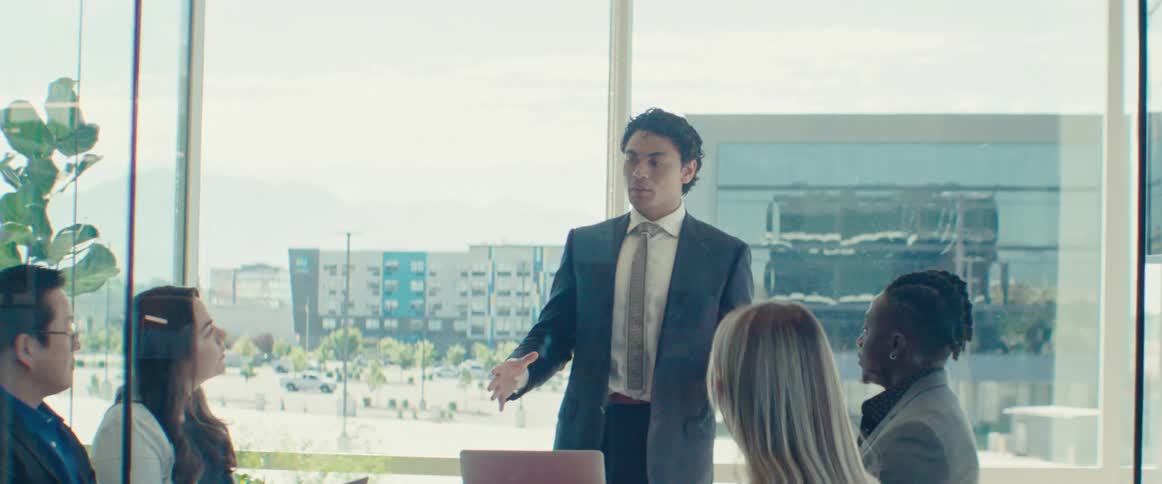 A man speaks to a small group of employees in an office