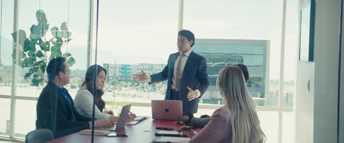 Man gestures while giving a presentation during an office meeting