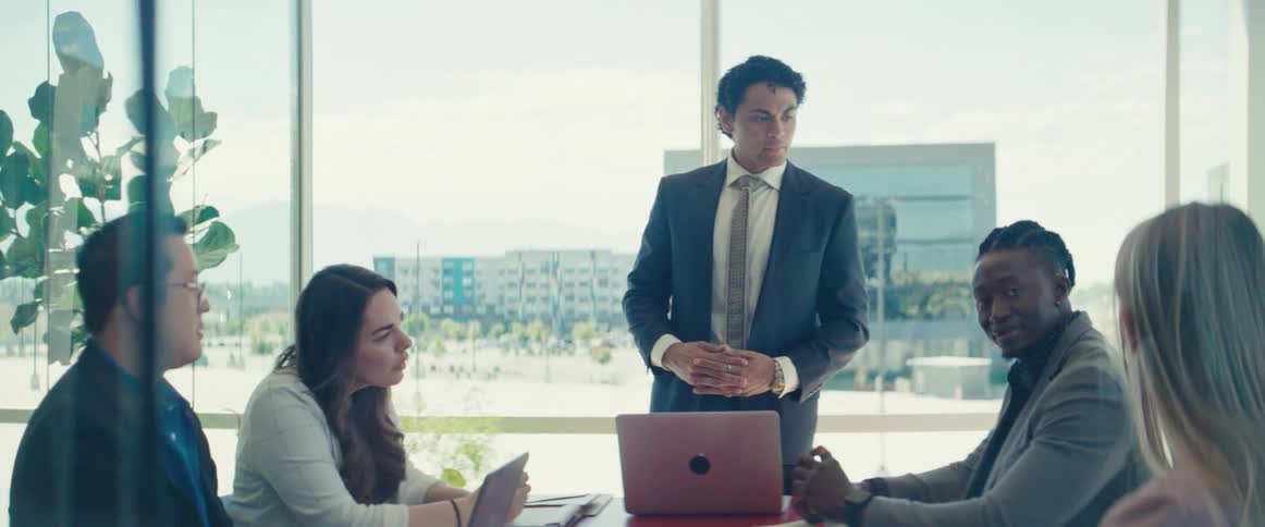 Man in suit standing talking to other people in an office room