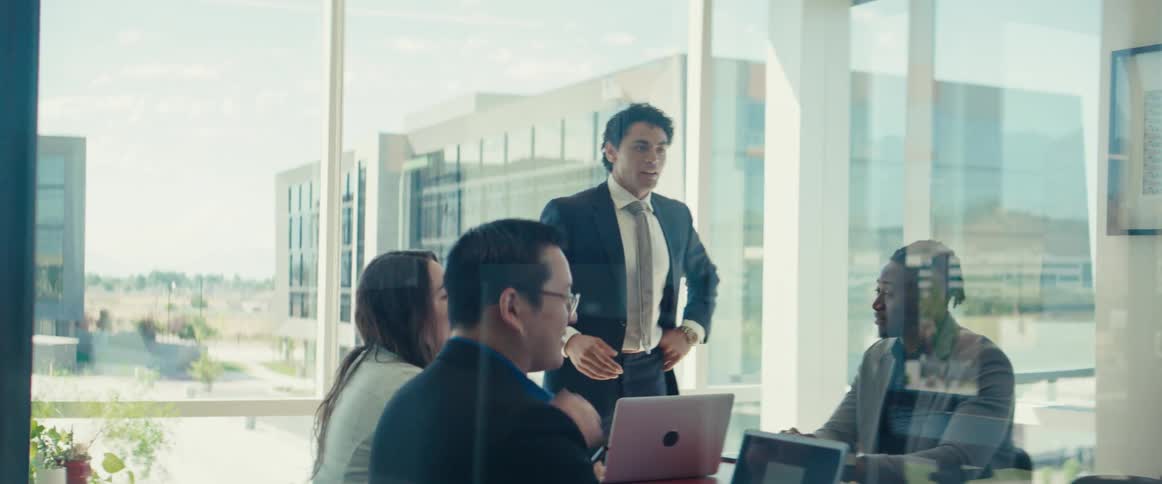 A man stands up in front of other workers and speaks while pacing