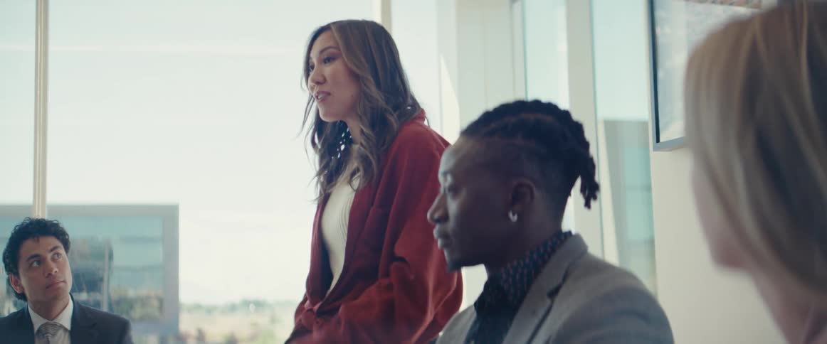 Woman standing talking to a group of people around her paying attention in an office environment