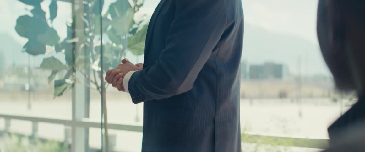A man walks by a sitting man in the office