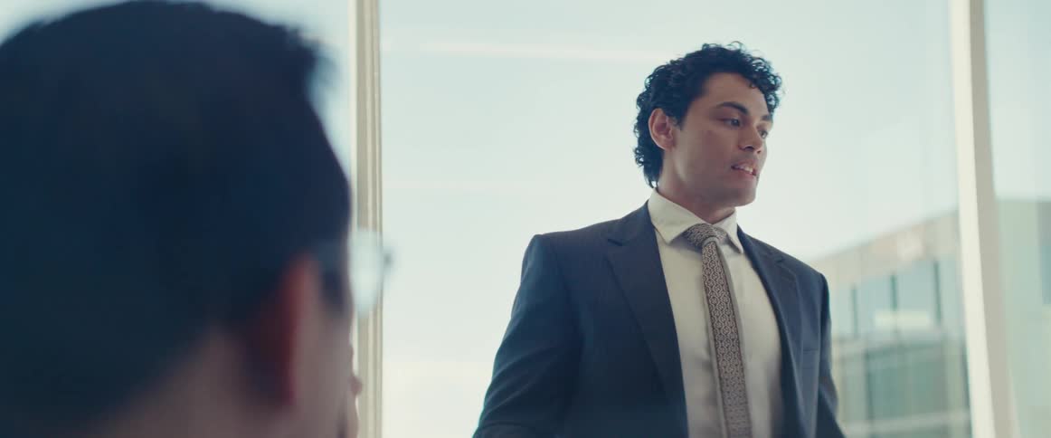 Man standing in suit talking to people sitting in an office environment