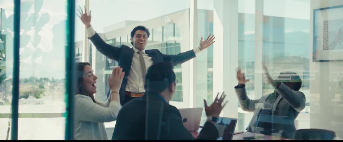 Group of people in an office throwing leaves into the air and clapping in celebration