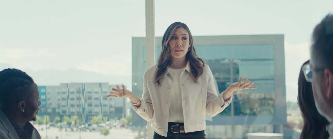 A young asian woman gives a presentation to other employees in an office setting