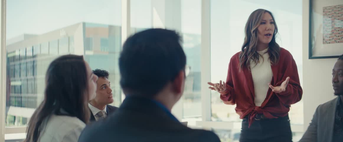 An asian woman speaks to coworkers in an office
