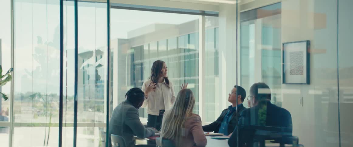 Colleagues gathered around a table in a modern office with large windows in a business meeting