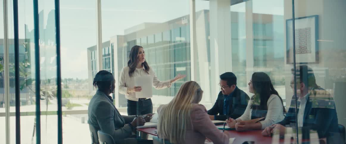 Woman standing and lecturing to a group of people sitting in an office