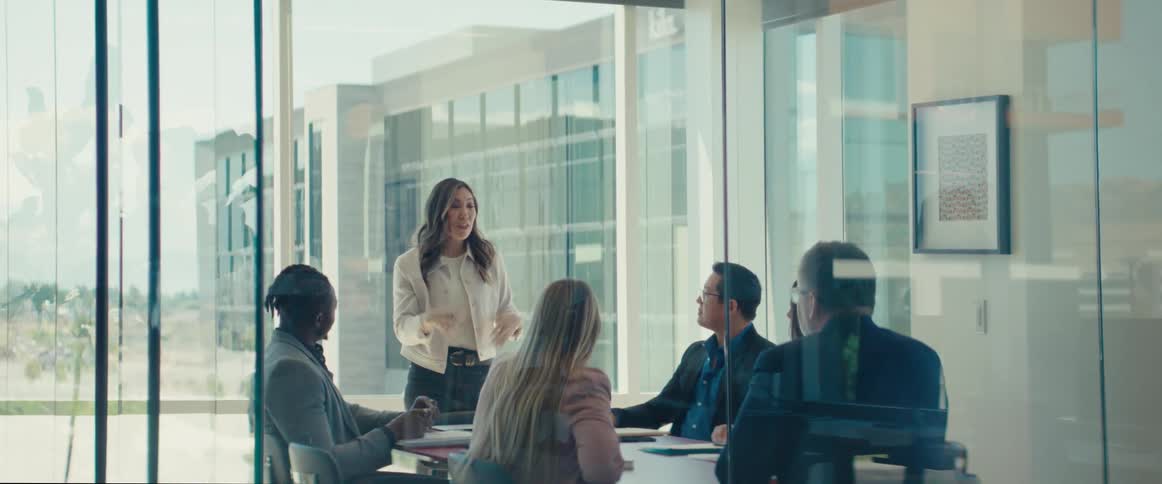 An asian woman speaks to a group of workers in an office