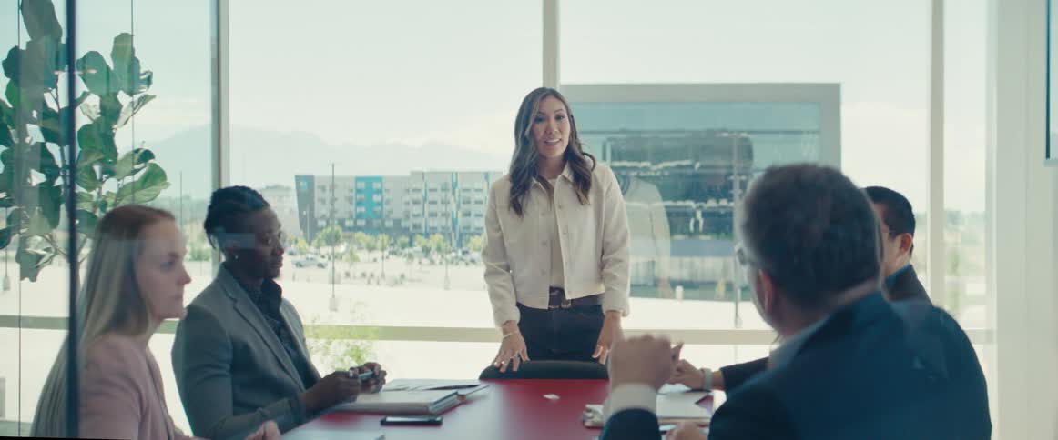 Colleagues gathered around a table in a modern office with large windows in a business meeting