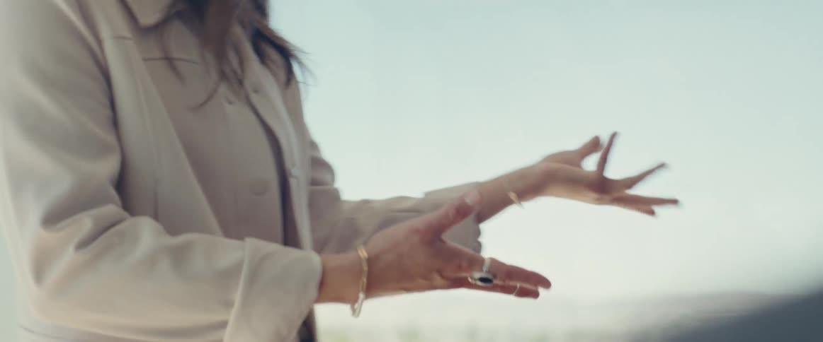 Woman standing gesturing with her hands and a man next to her paying attention
