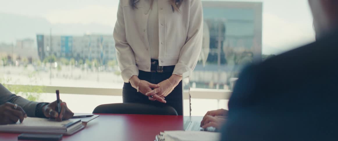 Woman standing in front of an office desk with people around