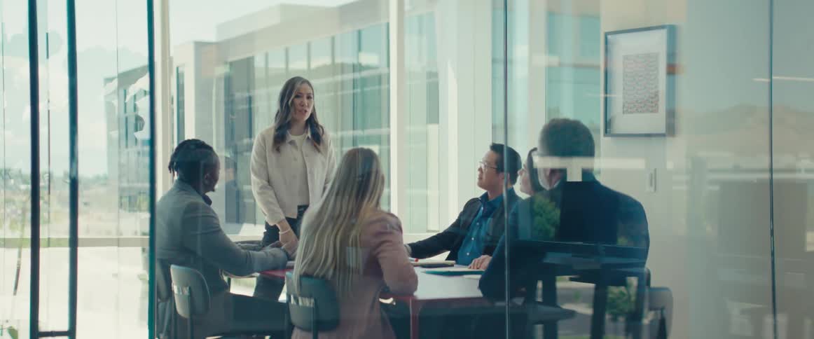 Colleagues gathered around a table in a modern office with large windows in a business meeting