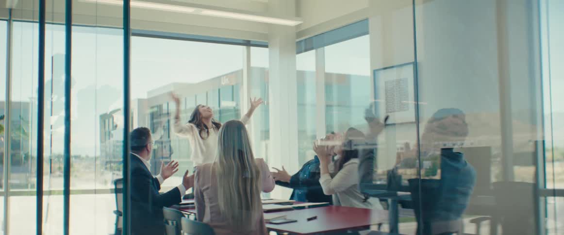 A group of office employees begin celebrating by throwing papers into the air