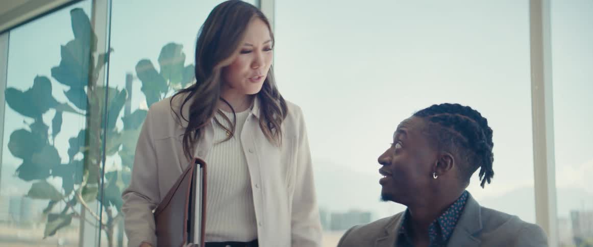 An asian woman talks to a black man in an office setting