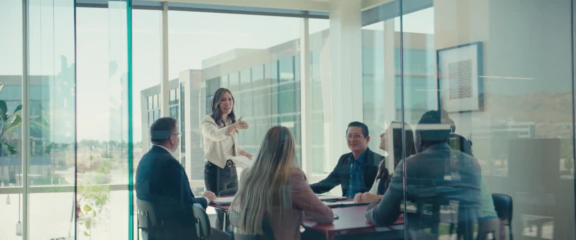 An asian woman speaks to workers in an office meeting