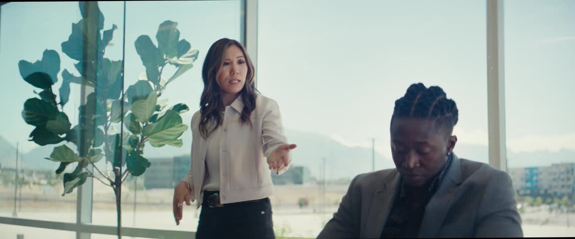 Woman standing and walking back and forth while a man is sitting both in an office environment